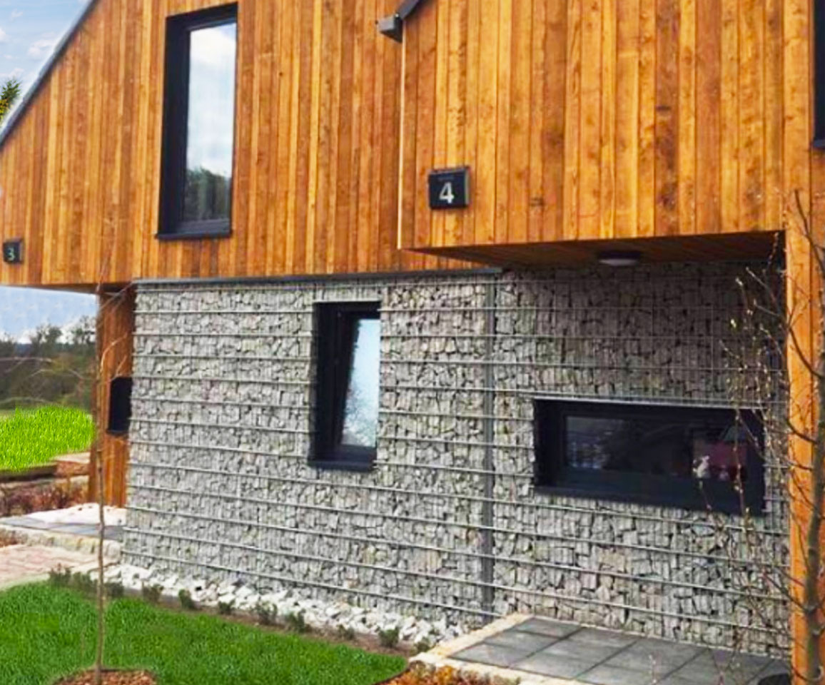 Kombination von Hauswänden aus Holz mit Gabionenverkleidung